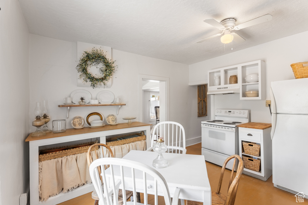 Kitchen featuring white appliances, under cabinet range hood, a ceiling fan, and white cabinetry