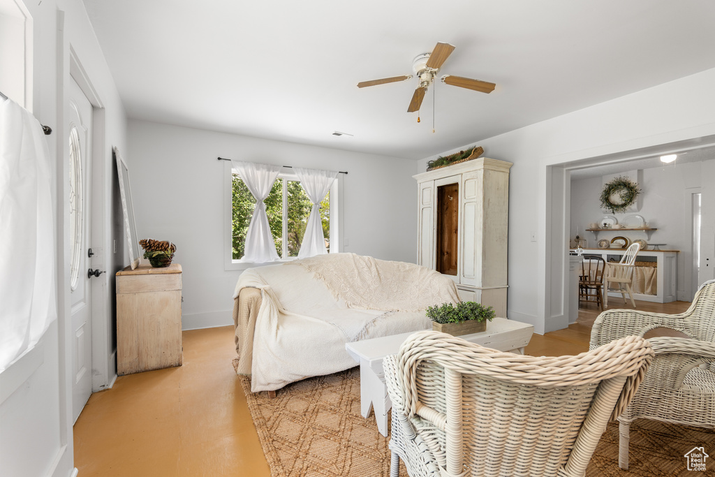 Living room featuring ceiling fan, baseboards, and finished concrete flooring