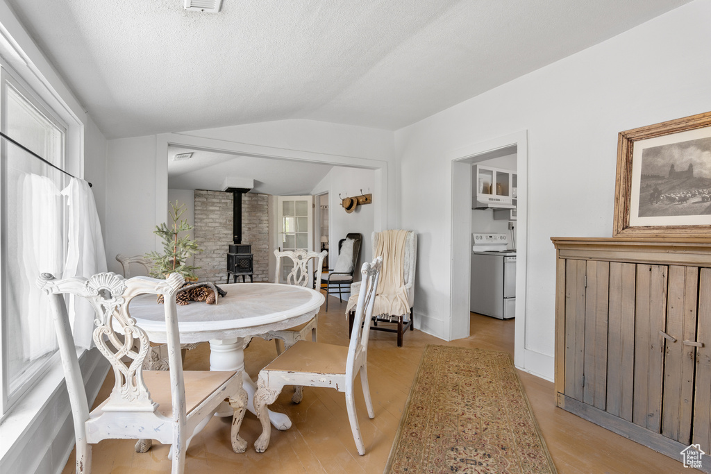 Dining area with a wood stove, lofted ceiling, and light wood finished floors