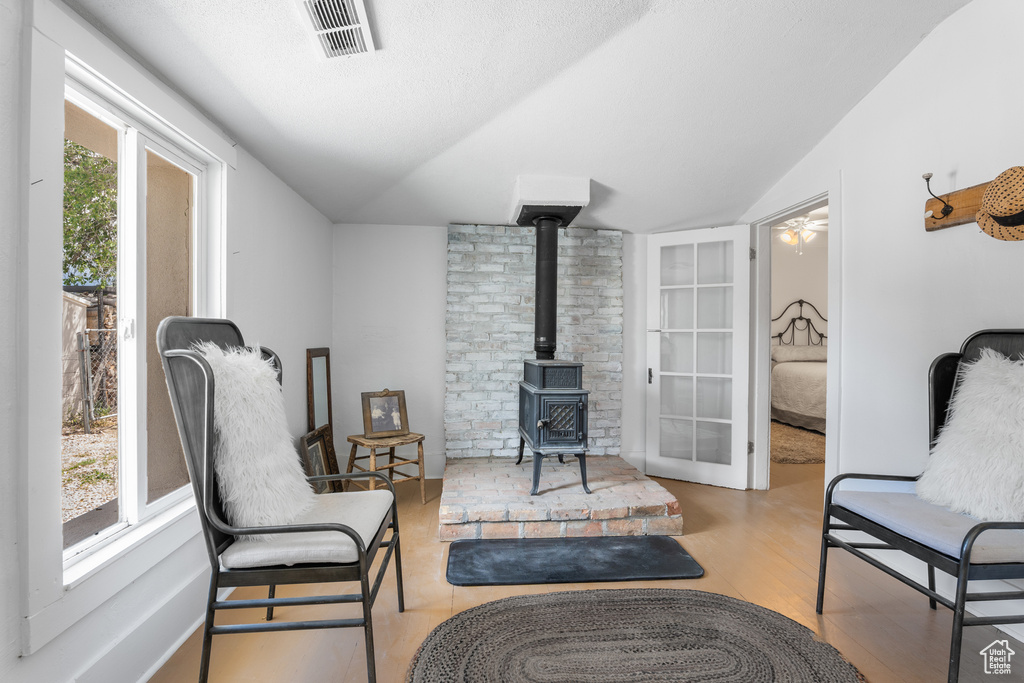 Sitting room with vaulted ceiling, a wood stove, and wood finished floors