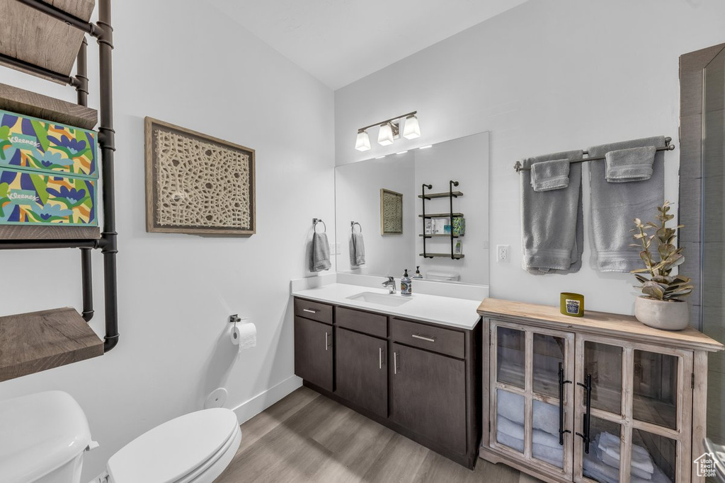 Bathroom with toilet, wood finished floors, vanity, and baseboards