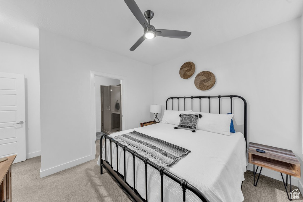 Bedroom with light colored carpet, baseboards, a ceiling fan, and ensuite bath