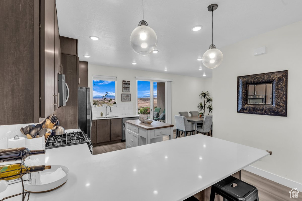 Kitchen featuring dark brown cabinets, light countertops, light wood-type flooring, a breakfast bar area, and a peninsula