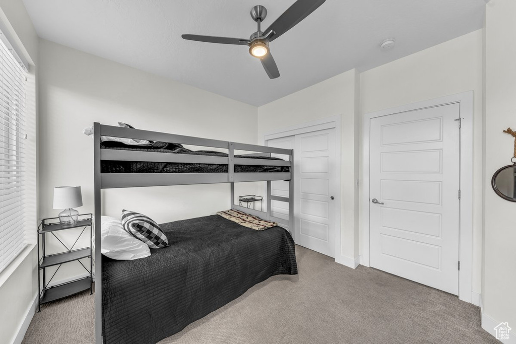Carpeted bedroom featuring baseboards, a ceiling fan, and a closet