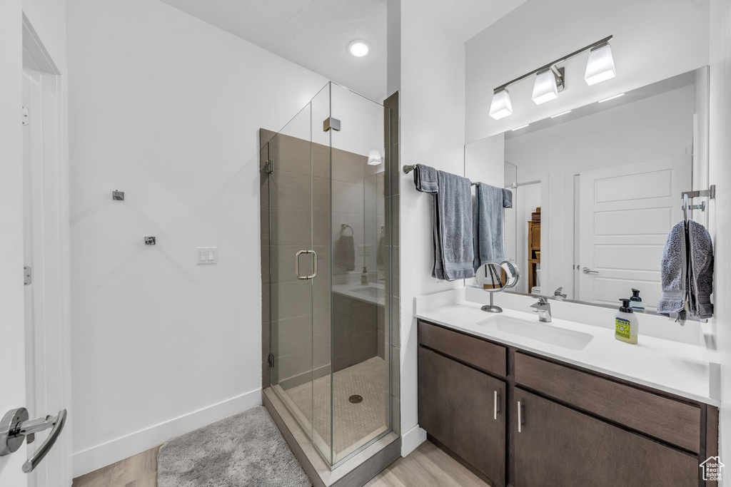 Bathroom with a stall shower, vanity, wood finished floors, and baseboards