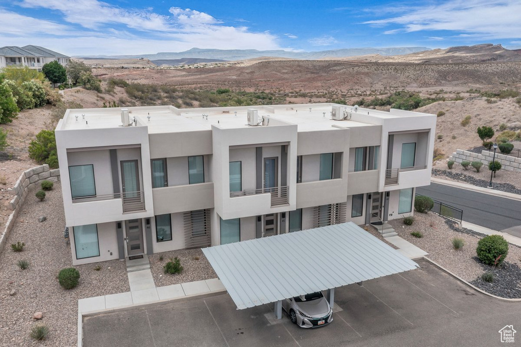 View of property with a mountain view and uncovered parking