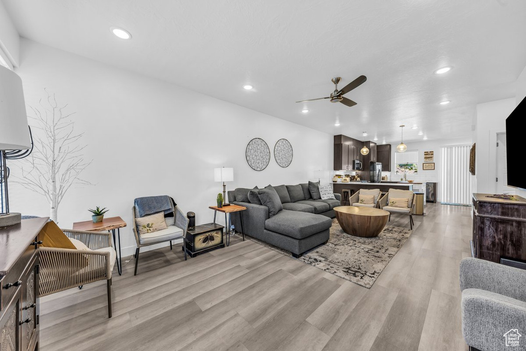 Living area with a ceiling fan, light wood finished floors, and recessed lighting