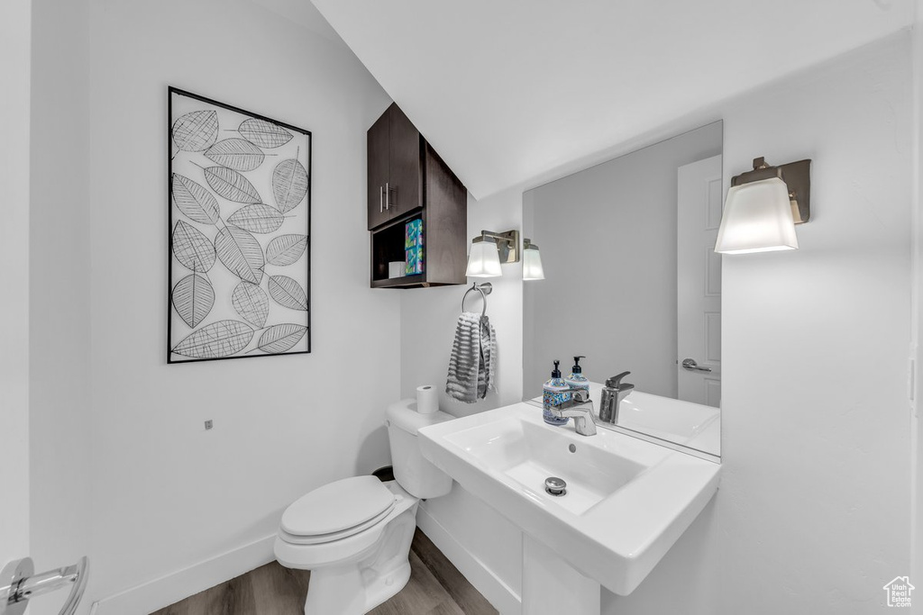 Half bathroom featuring a sink, wood finished floors, toilet, and baseboards