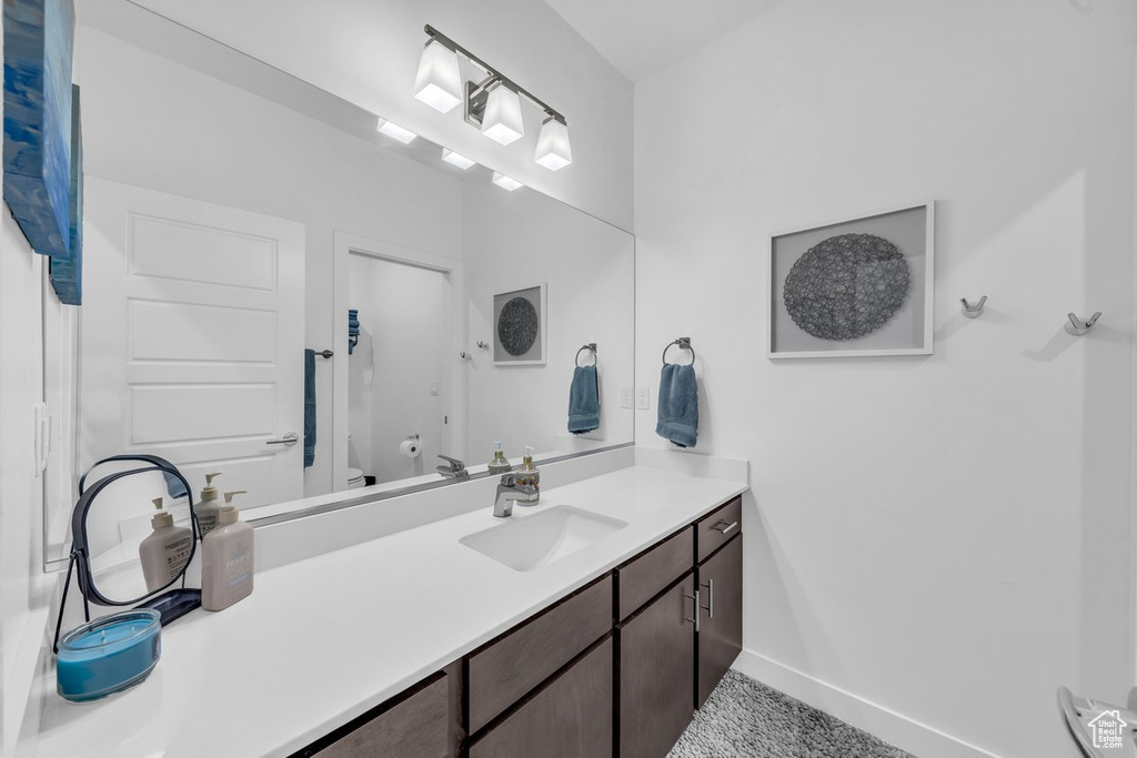 Full bathroom with toilet, vanity, and baseboards