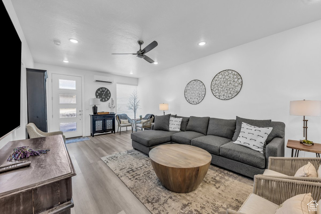 Living room with a ceiling fan, wood finished floors, a wall mounted air conditioner, and recessed lighting
