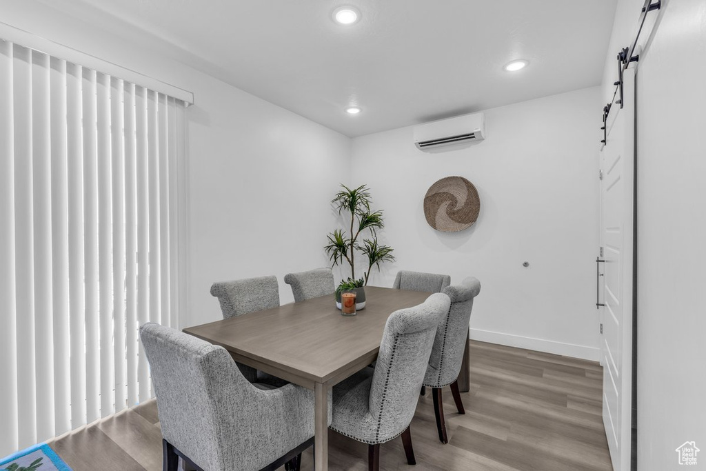 Dining space featuring an AC wall unit, light wood-style flooring, baseboards, recessed lighting, and a barn door