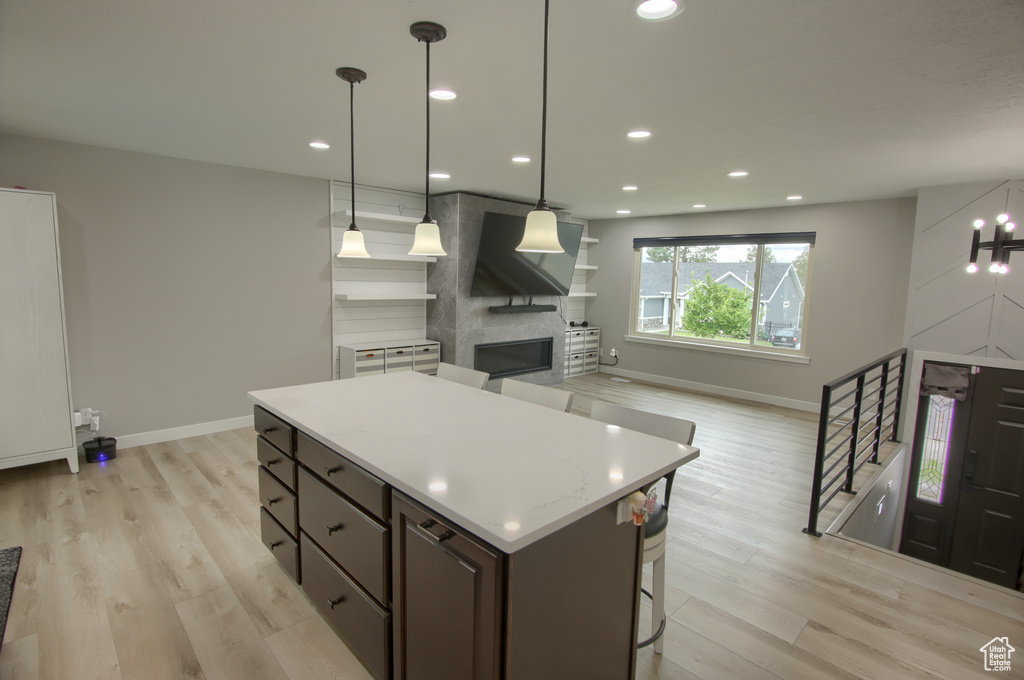 Kitchen with baseboards, a center island, light wood-type flooring, a fireplace, and recessed lighting