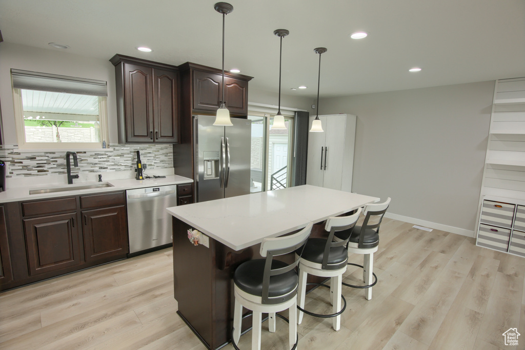 Kitchen featuring appliances with stainless steel finishes, a sink, light countertops, dark brown cabinets, and recessed lighting