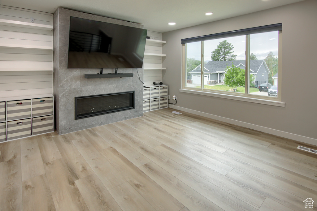 Unfurnished living room with baseboards, a fireplace, wood finished floors, and recessed lighting