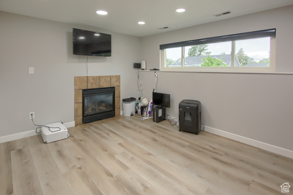 Living room featuring a tile fireplace, light wood-style flooring, baseboards, and recessed lighting