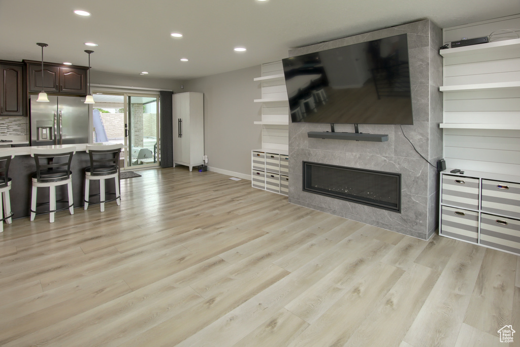 Living area with recessed lighting, light wood finished floors, a tiled fireplace, and baseboards