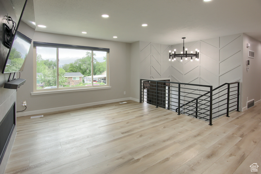 Unfurnished living room featuring a chandelier, baseboards, recessed lighting, and light wood-style floors