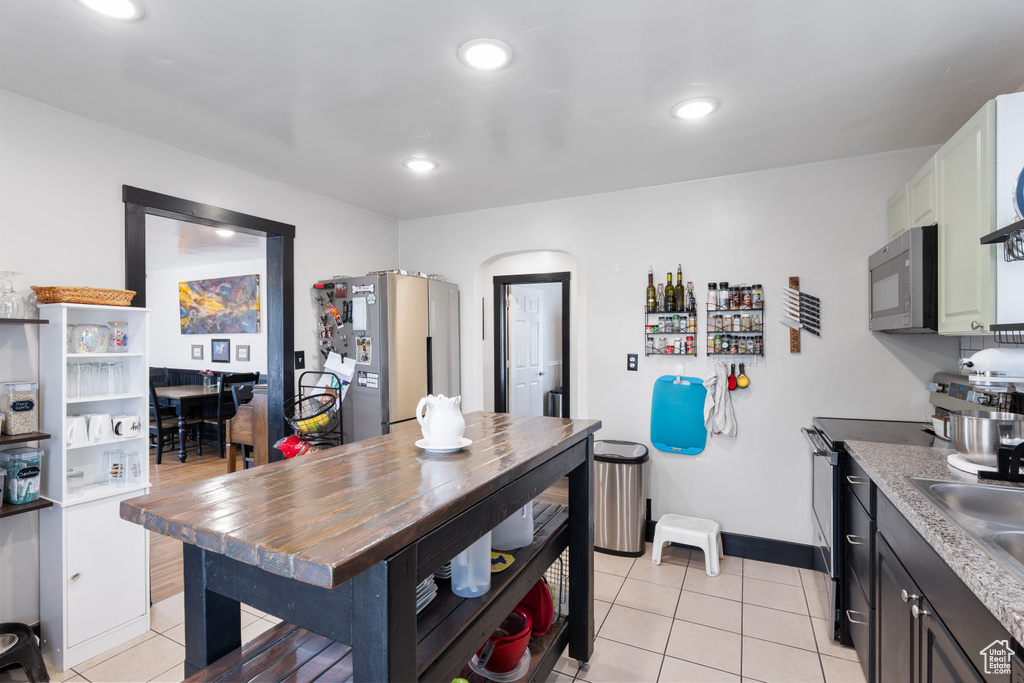 Kitchen with stainless steel appliances, light tile patterned flooring, baseboards, recessed lighting, and a sink