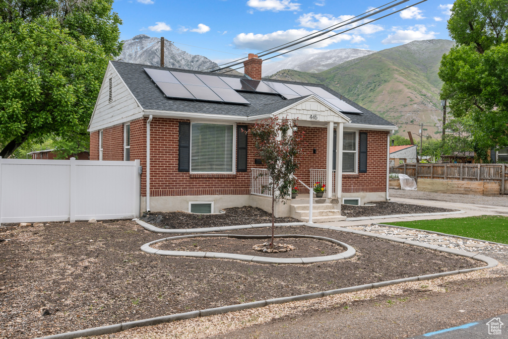 Bungalow-style house featuring brick siding, a chimney, a mountain view, and solar panels