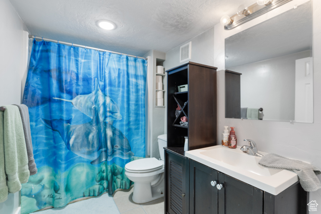 Full bathroom with a textured ceiling, toilet, vanity, tile patterned flooring, and a shower with shower curtain