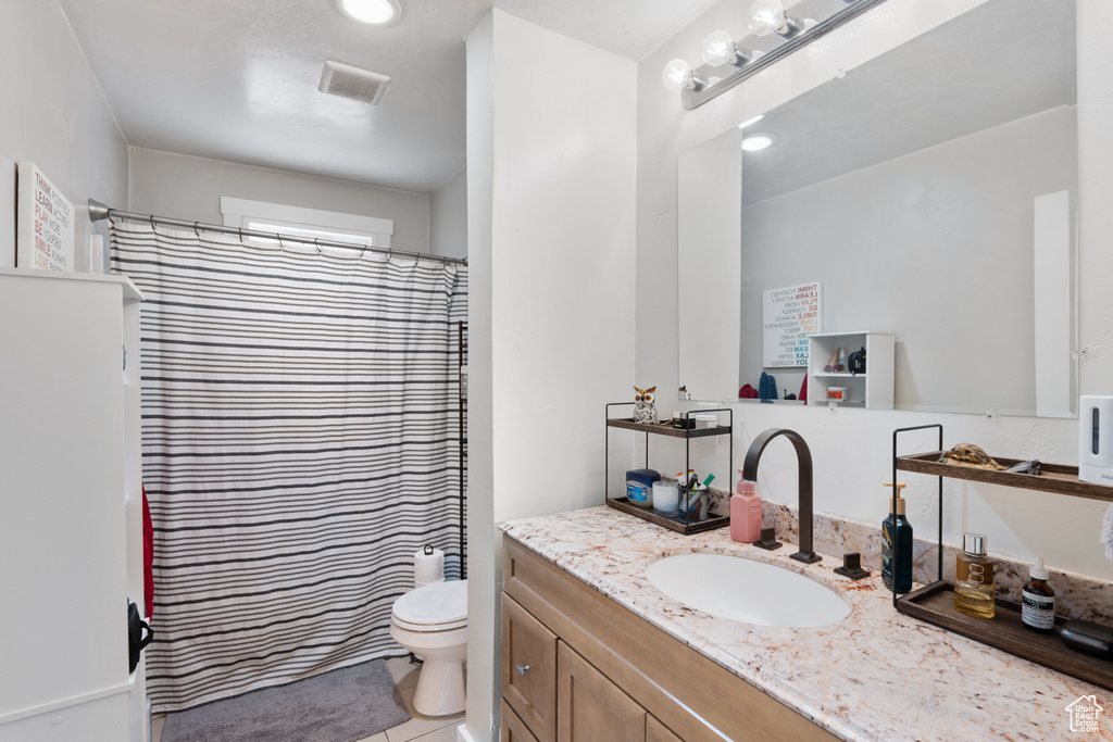 Bathroom with vanity, toilet, tile patterned flooring, and a shower with shower curtain