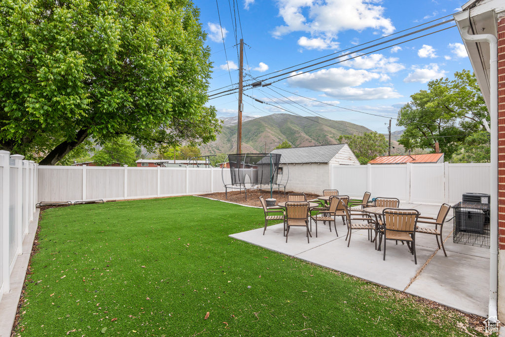 View of yard featuring a trampoline, a patio, and a mountain view