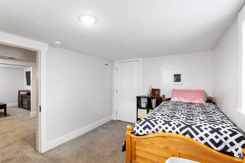 Bedroom with carpet flooring, baseboards, and a textured ceiling