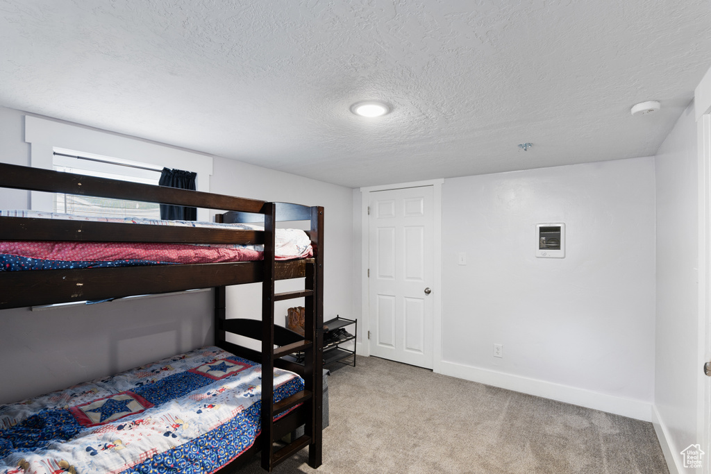 Carpeted bedroom featuring a textured ceiling and baseboards