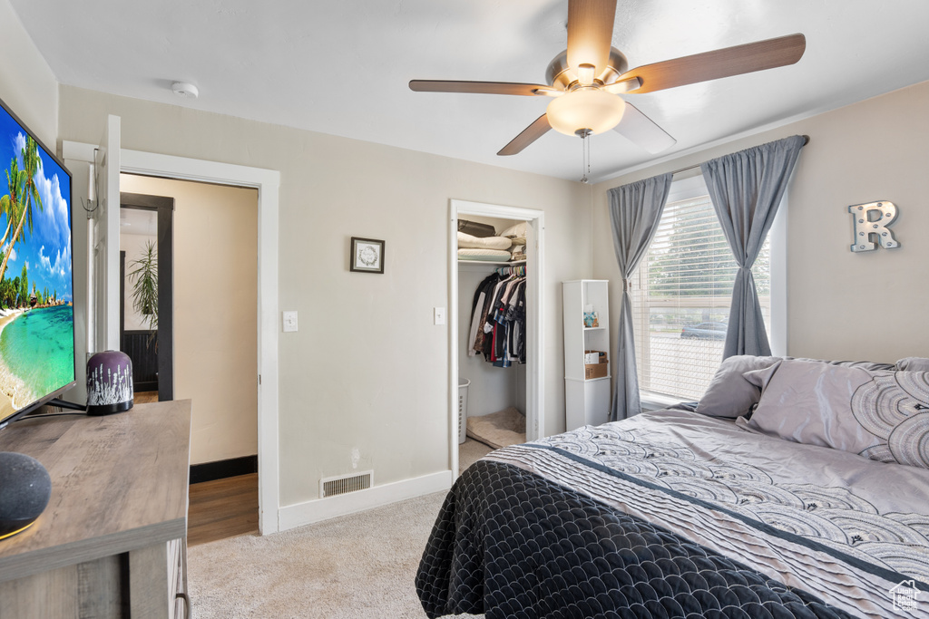 Bedroom with carpet flooring, baseboards, ceiling fan, a walk in closet, and a closet