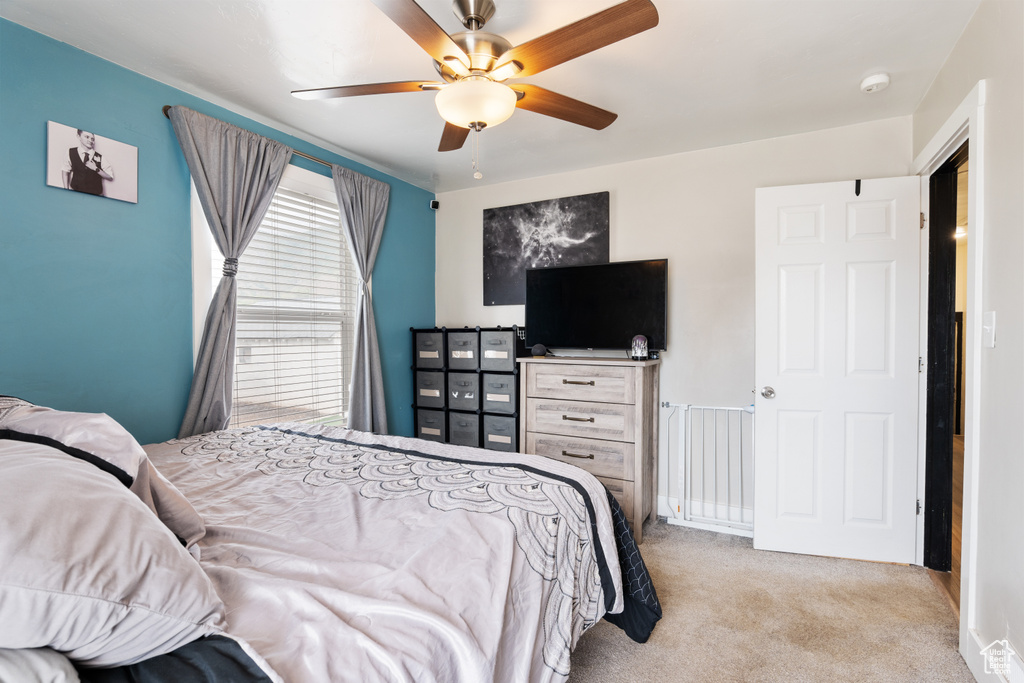 Carpeted bedroom with a ceiling fan