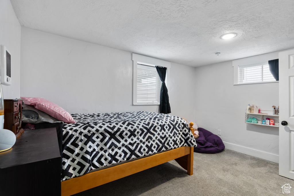 Bedroom with carpet, a textured ceiling, and baseboards