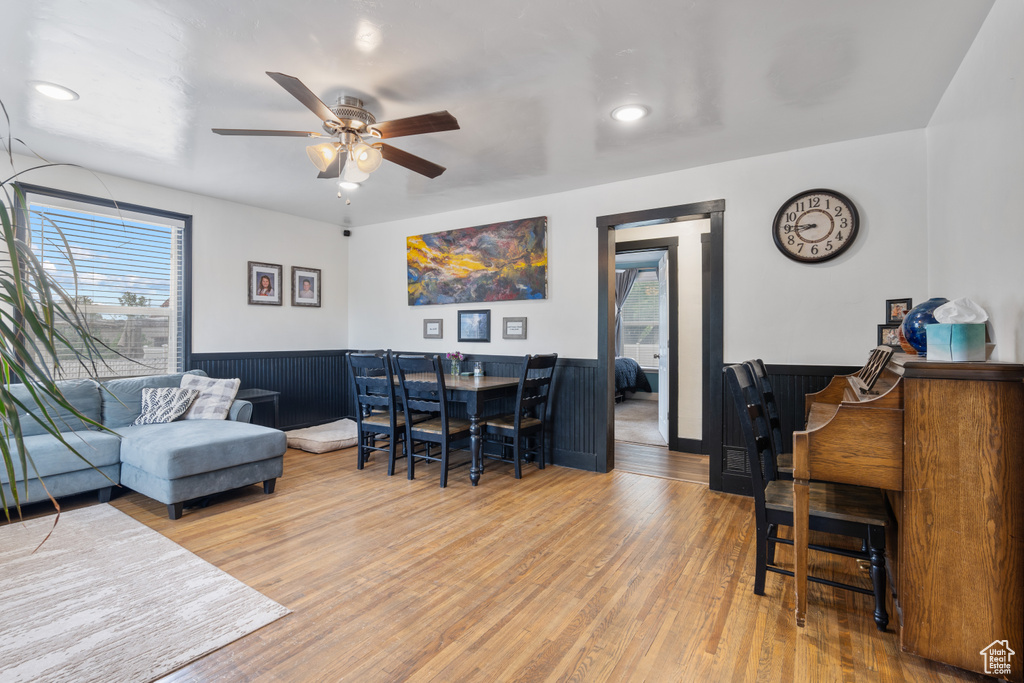 Living room featuring wood finished floors, a wainscoted wall, and a ceiling fan