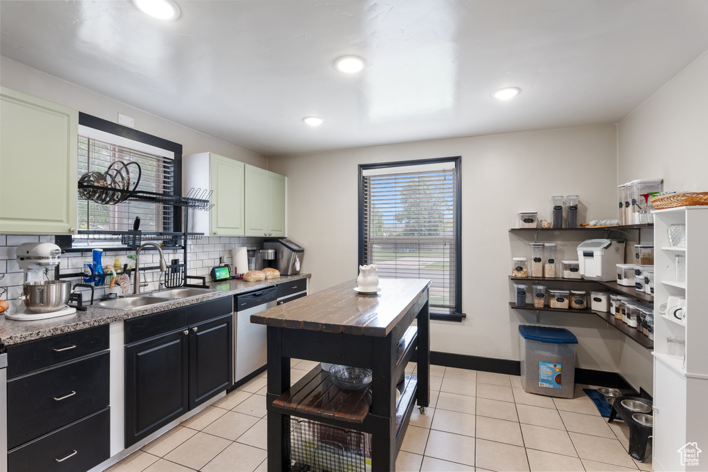 Kitchen with a sink, stainless steel dishwasher, backsplash, light tile patterned flooring, and recessed lighting