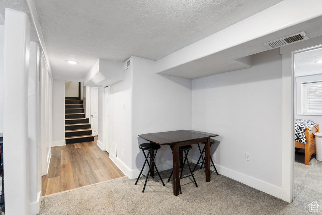 Basement with a textured ceiling, stairway, baseboards, carpet flooring, and wood finished floors