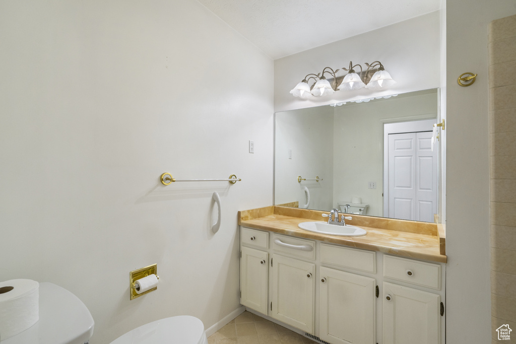 Bathroom with toilet, vanity, tile patterned floors, and baseboards