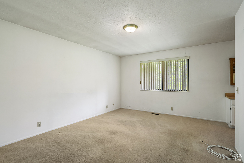 Carpeted empty room with baseboards and a textured ceiling