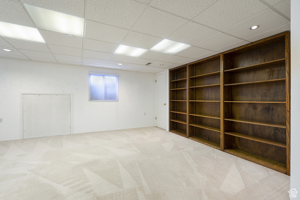 Carpeted empty room featuring built in features, a drop ceiling, recessed lighting, and baseboards