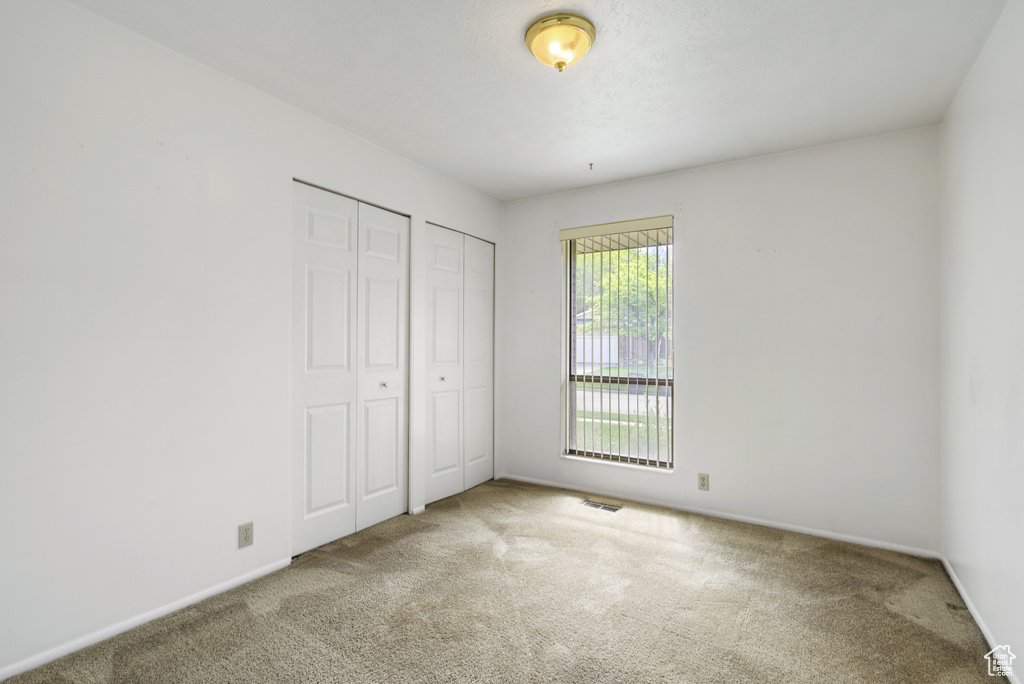 Unfurnished bedroom with carpet flooring, multiple closets, and baseboards