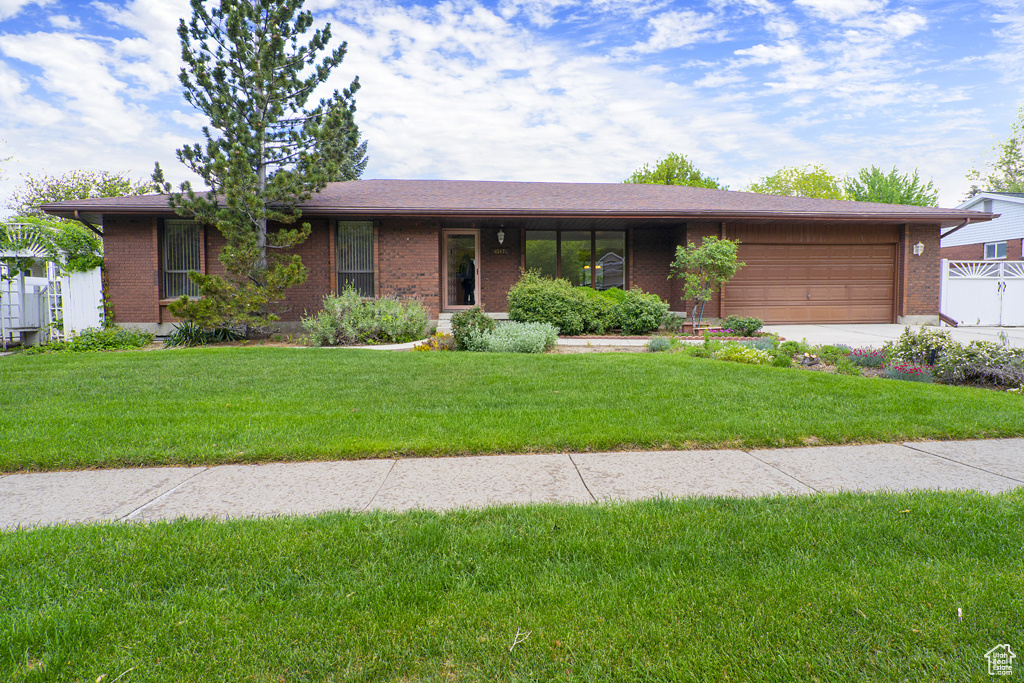 Ranch-style home featuring brick siding, an attached garage, a front lawn, and concrete driveway