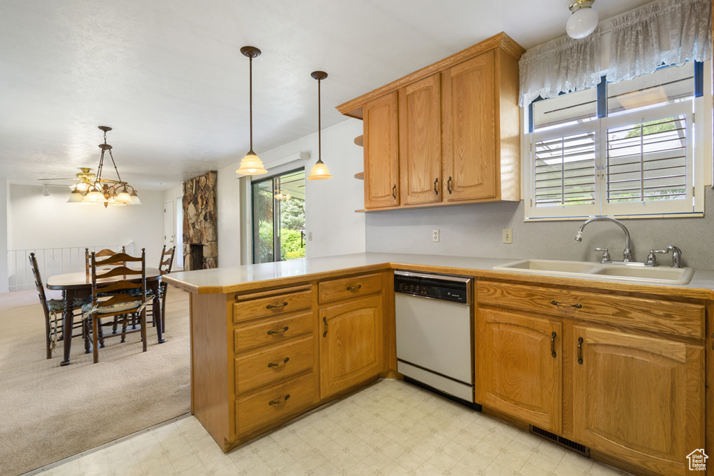 Kitchen featuring white dishwasher, a sink, light countertops, and a peninsula