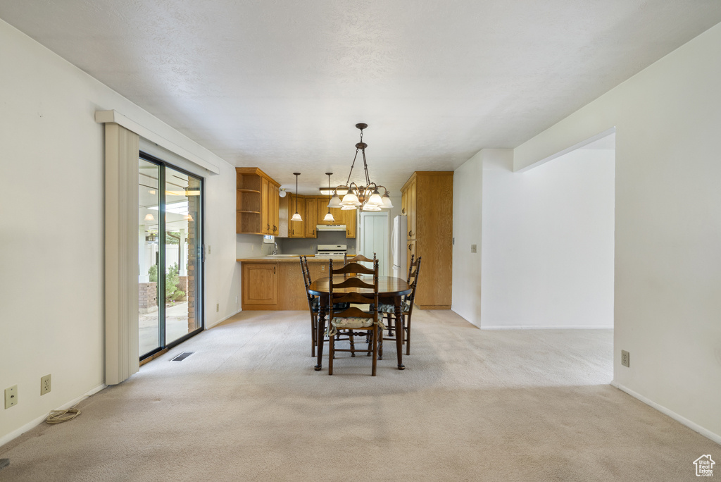 Dining area featuring a chandelier, light carpet, and baseboards