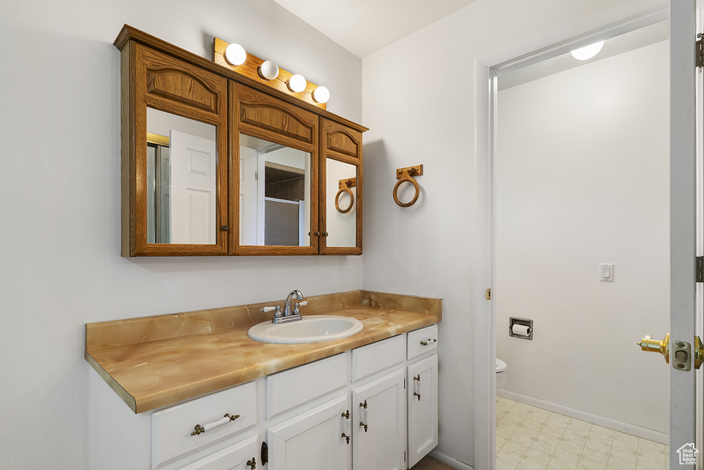 Bathroom with tile patterned floors, vanity, toilet, and baseboards