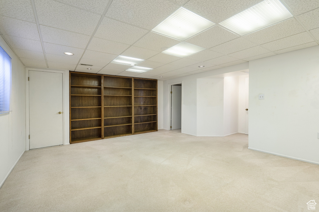 Carpeted spare room with built in features, a drop ceiling, and baseboards