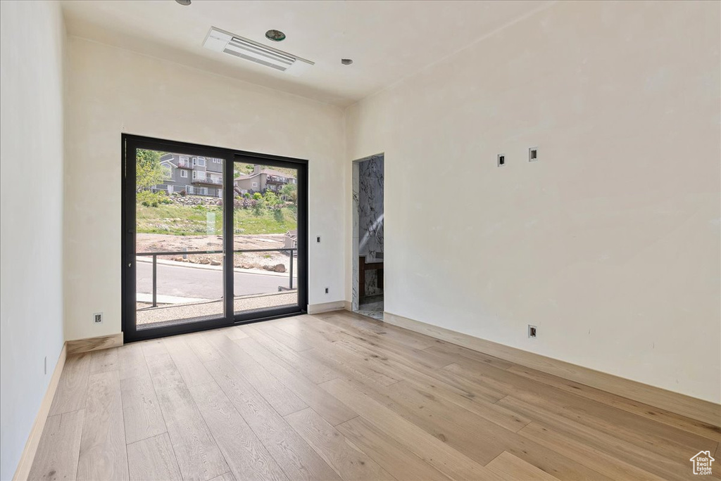 Empty room featuring light wood finished floors, baseboards, and a towering ceiling