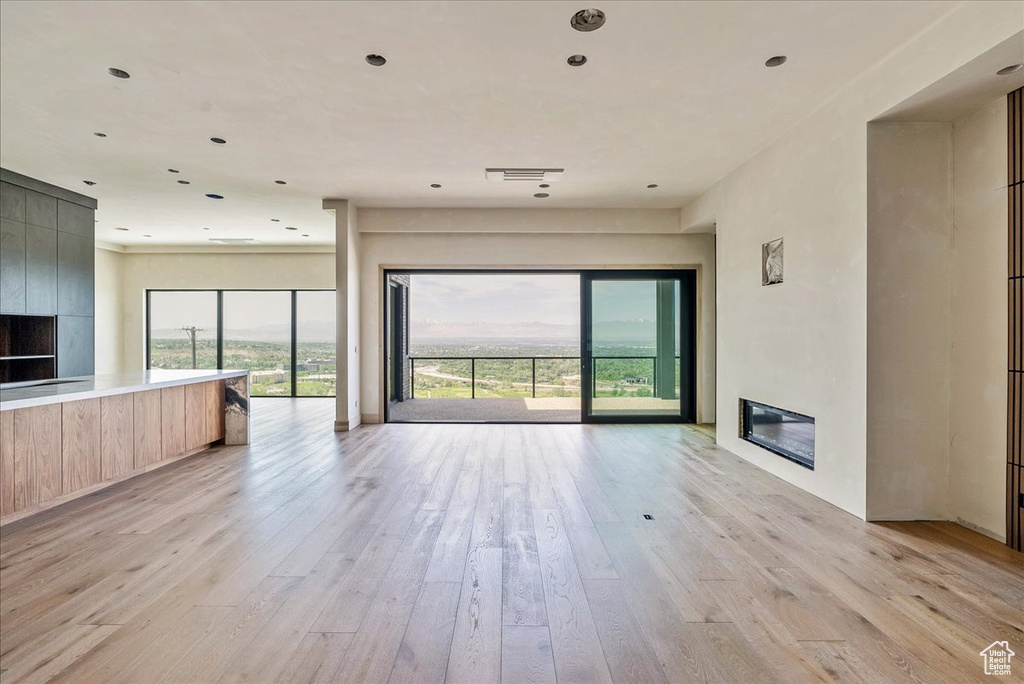 Unfurnished living room with a glass covered fireplace and light wood finished floors