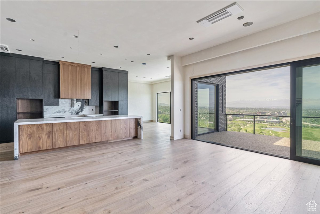 Kitchen with modern cabinets, light wood-type flooring, open floor plan, light countertops, and recessed lighting