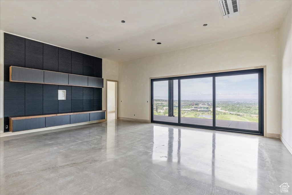 Empty room with concrete floors, baseboards, and a towering ceiling