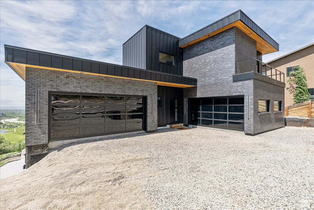 Modern home with board and batten siding, driveway, and brick siding