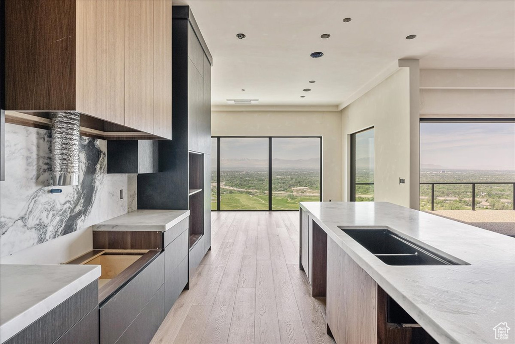 Kitchen with modern cabinets, light wood-style floors, light stone countertops, recessed lighting, and a sink