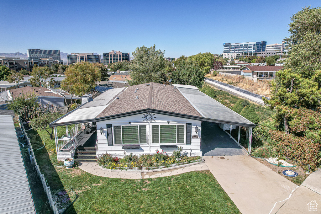 View of front of home featuring concrete driveway, a carport, a front lawn, and covered porch